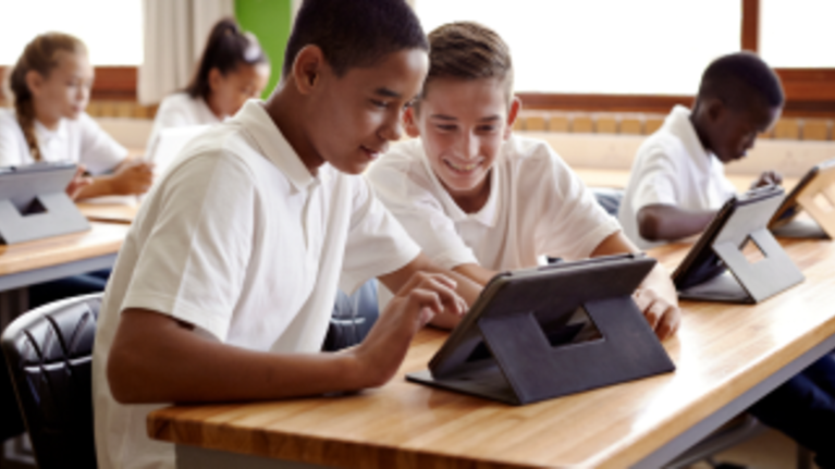 Students looking at tab in classroom